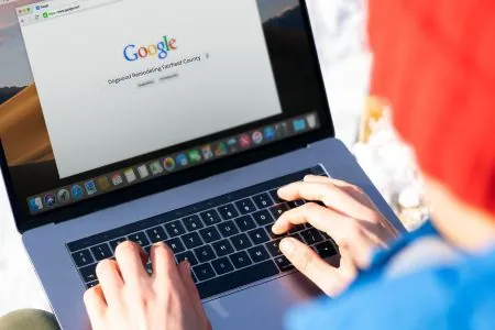 person using macbook pro with google website on screen